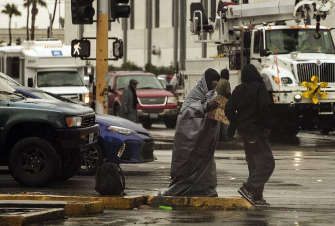 A homeless man wrapped  in a tarp continues to ask for donations along S. Las Vegas Blvd. as rain soaks the Las Vegas valley on Tuesday, Jan. 9, 2018.
