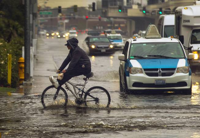 A bicyclist navigates standing water along E. Elvis Presley Blvd. as rain soaks the Las Vegas valley on Tuesday, Jan. 9, 2018.