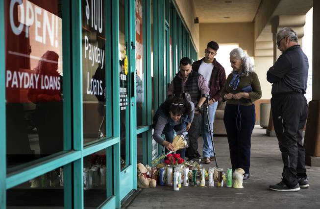 Family members visit a memorial grows for Celia Luna, she a store employee at the Express Cash Checking on Jones Boulevard near Vegas Drive who was recently killed there opening up by robbery suspects on Thursday, Jan. 18, 2018.