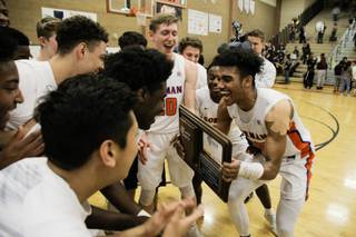 Bishop Gorman's Jamal Bey (35) holds the NIAA award and celebrates with his team after winning 57-46 against Clark during the Sunset Region Championship game at Legacy High School, Saturday, Feb. 17, 2018.