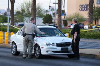 A Metro Police office and crime scene analyst look over damage to a Jaguar sedan after an auto-pedestrian accident on southbound Maryland Parkway in front of the Boulevard mall Tuesday, May 22, 2018.