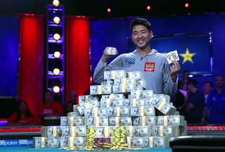 John Cynn holds up his championship bracelet and winning cards after his first place finish in the World Series of Poker Main Event at the Rio Sunday morning, July 15, 2018. Cynn won the bracelet and $8.8 million in prize money.