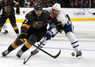 Vegas Golden Knights defenseman Shea Theodore (27) and Toronto Maple Leafs left wing Zach Hyman (11) chase after a puck during the second period at T-Mobile Arena Thursday, Feb. 14, 2019.