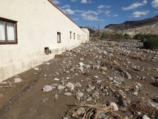 Mud, rocks, and other flood debris washed up against the side of a building. credit: NPS