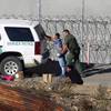 In this Dec. 15, 2018, file photo, Honduran asylum seekers are taken into custody by U.S. Border Patrol agents after the group crossed the U.S. border wall into San Diego, Calif., seen from Tijuana, Mexico. Immigrant rights activists on Friday, June 28, 2019, asked a U.S. judge to block a new Trump administration policy that would keep thousands of asylum seekers locked up while they pursue their cases, instead of giving them a chance to be released on bond.