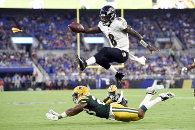 Baltimore Ravens quarterback Lamar Jackson (8) leaps over Green Bay Packers cornerback Jaire Alexander (23) during the first half of a preseason game in Baltimore.