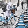 Photo: A woman clears off a Divvy bike as a winter weathe Photo: A woman clears off a Divvy bike as a winter weathe