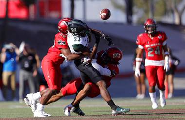 Hawaii Warriors wide receiver Jared Smart (23) fumbles the ball as he is tackled by UNLV Rebels defensive back Aaron Lewis, left, and defensive back Evan Austrie (17) during a game against the Hawaii Warriors at Sam Boyd Stadium Saturday, Nov. 16, 2019. UNLV recovered the fumble. 