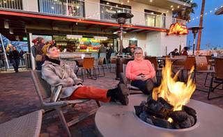 Heidi Rider, left, and Vicky Blake warm up by the fire pit at the La Monja Cantina during the Fergusons Downtown grand opening at 1028 Fremont St. in Las Vegas on Friday, Dec. 13, 2019. Fergusons Downtown is a former hotel converted to a retail, restaurant and entertainment space.