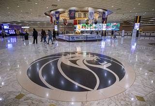 People walk though a nearly-empty lobby Sunday, March 15, 2020. MGM Resorts International announced it will temporarily suspend operations at its Las Vegas properties beginning Monday to help thwart the spread of the coronavirus.