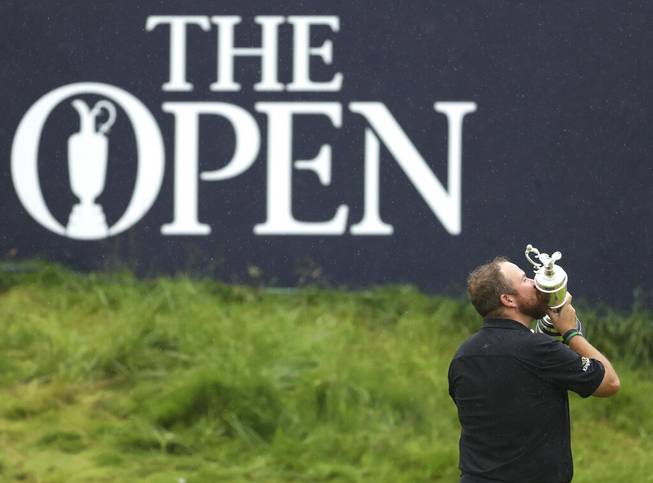 In this Sunday, July 21, 2019 file photo Ireland's Shane Lowry holds and kisses the Claret Jug trophy on the 18th green as he poses for the crowd and media after winning the British Open Golf Championships at Royal Portrush in Northern Ireland.