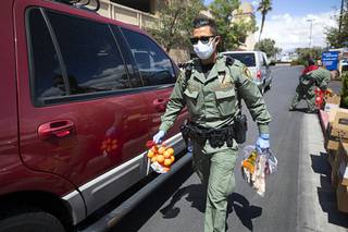 Metro Police Officer Sergio Felix puts produce in a car during a drive-thru Three Square food distribution at Palace Station Thursday, April 9, 2020.