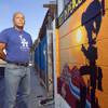 Marine veteran Cesar Lopez poses by a mural on a wall outside his home Wednesday, Aug. 12, 2020. Lopez, a legal resident, was deported to Mexico over a conviction from 2000. He now works on behalf of other veterans who have been deported.