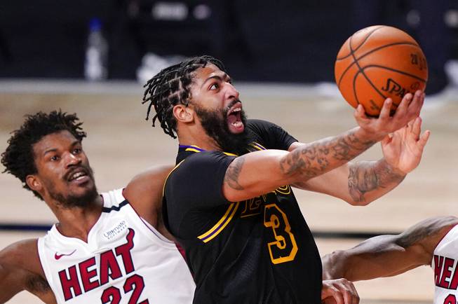 In this Oct. 9, 2020, file photo, Los Angeles Lakers forward Anthony Davis shoots past Miami Heat forward Jimmy Butler during the second half in Game 5 of basketball's NBA Finals in Lake Buena Vista, Fla. 
