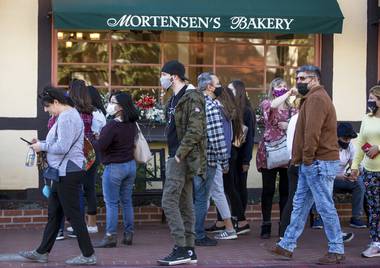 Groups of people, some wearing masks, take over the sidewalks downtown in Solvang, California, on Nov. 28, 2020. It was almost two weeks ago that the popular California tourist town of Solvang made headlines when it said it wouldn’t enforce Gov. Gavin Newsom’s tough new stay-at-home orders. But that was a week before a new City Council took over and told everyone to obey the rules to save lives.