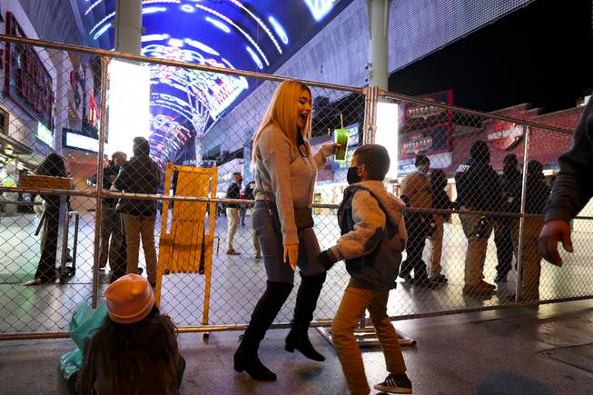 Alondra Aguilar and her son Romeo Aguilar, 6, dance near a fence blocking access to the Fremont Street Experience, downtown, Thursday, Dec. 31, 2020. "We're just waiting for something to happen. Until then we're gonna party here." Aguilar said.