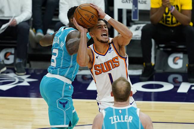 Phoenix Suns guard Devin Booker (1) drives past Charlotte Hornets guard Terry Rozier (3) during the second half of an NBA basketball game, Wednesday, Feb. 24, 2021, in Phoenix.
