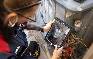Nikki Kahalehili, a service technician with Goettl Air Conditioning and Plumbing, takes a photo of a capacitor in an air conditioning unit during a service call Thursday Aug. 5, 2021.