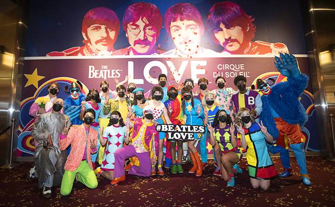 Cast members of The Beatles LOVE by Cirque du Soleil pose at the theater box office as they celebrate their reopening night at the Mirage Thursday, Aug. 26, 2021.