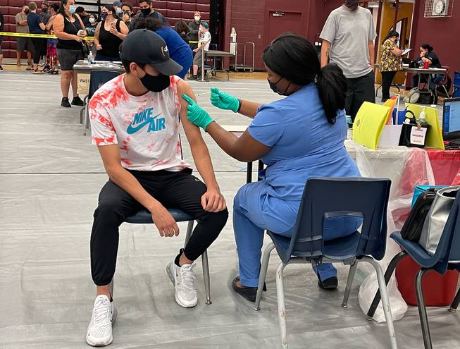 Ethan Lucero, 19, of Las Vegas receives a dose of the Pfizer-BioNTech COVID-19 vaccine at Eldorado High School in Las Vegas on Saturday, Sept. 18, 2021. Lucero was one of 500 people on Saturday to receive a $100 gift card for getting the shot, as part of a new Clark County pilot program. 
