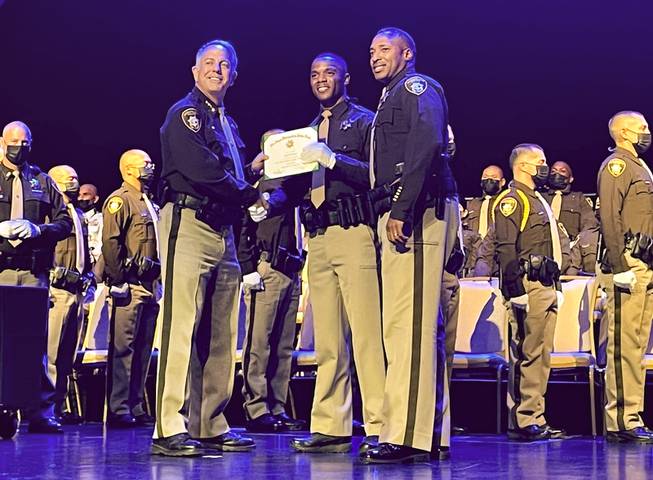 Sheriff Joe Lombardo, left, shakes hands with graduating officer Russell Booze, center, during Metro Police’s graduation ceremony at the Orleans, Wednesday, Oct. 6, 2021.