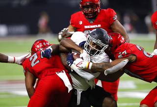 Utah State Aggies running back Calvin Tyler Jr. (4) is stopped by UNLV Rebels defensive back Bryce Jackson (24) and linebacker Austin Ajiake (27) during the first half of an NCAA football game against Utah State at Allegiant Stadium Saturday, Oct. 16, 2021. 