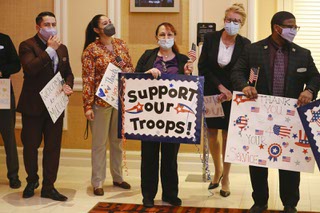 MGM Resorts employee volunteers hold signs showing support to troops during the United Service Organization (USO) Salute to the Troops event hosted by MGM Resorts International honoring 95 wounded warriors and their guests at The Mirage Thursday, Nov. 4, 2021.