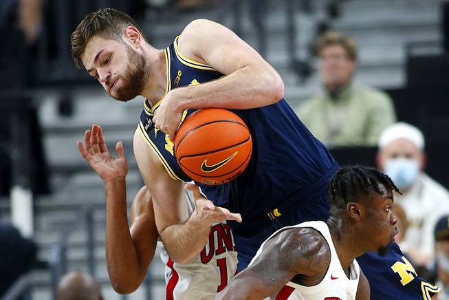 Michigan Wolverines center Hunter Dickinson (1) takes the ball between UNLV Rebels forward Royce Hamm Jr. (14) and guard Michael Nuga (1) during a game in the Roman Main Event tournament at T-Mobile Arena Friday, Nov. 19, 2021.