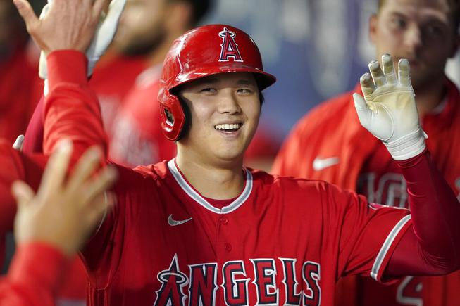 Los Angeles Angels' Shohei Ohtani is greeted in the dugout after he hit a solo home run during the first inning of a baseball game against the Seattle Mariners, Sunday, Oct. 3, 2021, in Seattle.