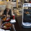 A Richtech Robotics Matradee robot delivers food to Maurice Smith and Najee Smith at Catchers Fish House Friday, Feb. 11, 2022. Employees have named the robot Caribbean Mike.