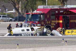 Officials investigate the wreckage of a plane at the site of a fatal crash at the North Las Vegas Airport, Sunday, July 17, 2022, in North Las Vegas, Nev. Authorities say several people are dead after two small planes collided at North Las Vegas Airport.