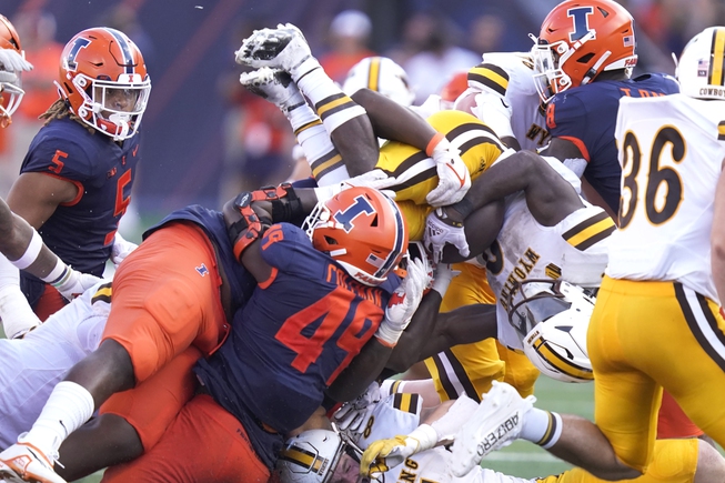 Illinois defensive lineman Calvin Avery, second from left, and linebacker Seth Coleman (49) tackle Wyoming running back Titus Swen during the second half of an NCAA college football game Saturday, Aug. 27, 2022, in Champaign, Ill.