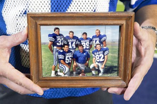 Jeremy Richter displays a photo from his high school days during an interview at Green Valley High School in Henderson Wednesday, Sept. 21, 2022. Richter is at top right. Pictured are: back row, Richie Montano (32), Eric Oliver (14), Jeff Cahill (89) and Richter (44). Front row from left are: Gilbert Medina (55), coach Dan Cahill, and Chad Brandon (82).