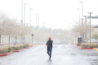 A person walks as snow falls in Downtown Summerlin Tuesday, Feb. 14, 2023.