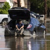 Dorian Padilla sits in his car as he waits for a tow after it got stuck in the mud on a street Monday, Aug. 21, 2023, in Cathedral City, Calif.