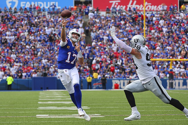 Buffalo Bills quarterback Josh Allen, left, throws a pass over Las Vegas Raiders' Maxx Crosby (98) for a touchdown during the second half of an NFL football game, Sunday, Sept. 17, 2023, in Orchard Park, N.Y. (AP Photo/Jeffrey T. Barnes)