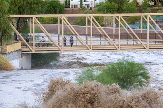 People take photos of rain runoff flowing through the Pitman Wash at Arroyo Grande Boulevard after afternoon storms Wednesday, Sept. 20, 2023, in Henderson.