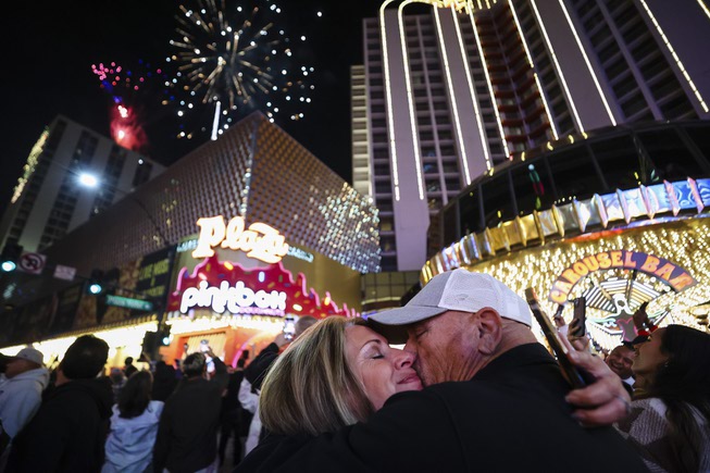 A couple share a moment as fireworks explode over the Plaza in Downtown Las Vegas on New Years Eve Monday Jan. 1, 2024.