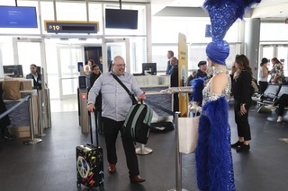 A passenger receives a cookie from a showgirl as he de-boards Porter Airlines’ inaugural flight between Toronto, Canada and Las Vegas at Harry Reid International Airport Tuesday, March 5, 2024.