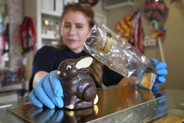 Niaz Mardan wraps a luxury handmade Belgian chocolate rabbit at Sandrine a chocolate shop in south west London, Thursday, March 21, 2024.