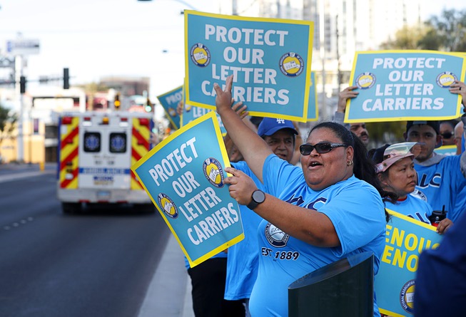 Letter carrier Shirley McGee holds up a sign during a demonstration by letter carriers in front of the Lloyd George Federal Building in downtown Las Vegas Wednesday, April 17, 2024. The demonstration was organized by the National Association of Letter Carriers, the national labor union of city delivery letter carriers employed by the United States Postal Service.
