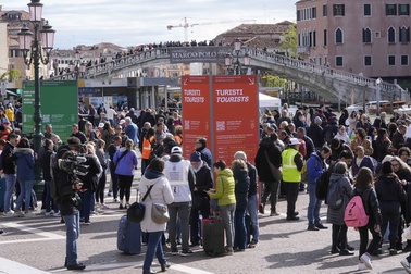 Stewards check tourists QR code access outside the main train station in Venice, Italy, Thursday, April 25, 2024.