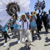Members of the Zulu Steppers parade with the New Groove Brass Band along the Fair Grounds at the New Orleans Jazz and Heritage Festival in New Orleans, Thursday, April 25, 2024.