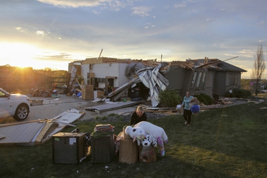 Two women help carry a friend's belongings out of their damaged home after a tornado passed through the area in Bennington, Neb., Friday, April 26, 2024. 