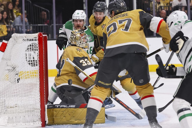 Vegas Golden Knights defenseman Shea Theodore (27) tries to clear the puck away from Vegas Golden Knights goaltender Adin Hill (33) during the second period of Game 6 of an NHL hockey Stanley Cup first-round playoff series against the Dallas Stars at T-Mobile Arena Friday, May 3, 2024.