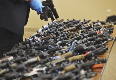 Dozens of recovered stolen handguns are displayed during a press conference, Nov. 21, 2023, in Benton Township, Mich. 
