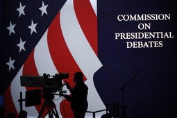 A cameraman is silhouetted against an an American flag during preparations for the presidential debate at Hofstra University in Hempstead, N.Y., Sept. 25, 2016. The nonpartisan Commission on Presidential Debates, which has planned presidential faceoffs in every election since 1988, has an uncertain future after President Joe Biden and former President Donald Trump struck an agreement to meet on their own. 


