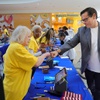 Nevada Secretary of State Cisco Aguilar bumps fists with poll worker Patsy Salazar as Darlene Russell looks on at a polling site in the Galleria At Sunset mall in Henderson Tuesday, June 11, 2024.
