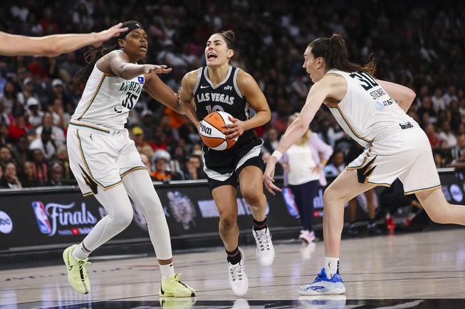 Las Vegas Aces guard Kelsey Plum (10) drives to the basket against New York Liberty forward Jonquel Jones (35) and New York Liberty forward Breanna Stewart (30) during the second half of a WNBA basketball game Saturday, June 15, 2024, in Las Vegas.