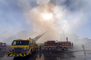 The sun shines through a column of smoke as City of Las Vegas and Clark County firefighters put water on a fire at an apartment complex west of Clark High School Wednesday, July 3, 2024.